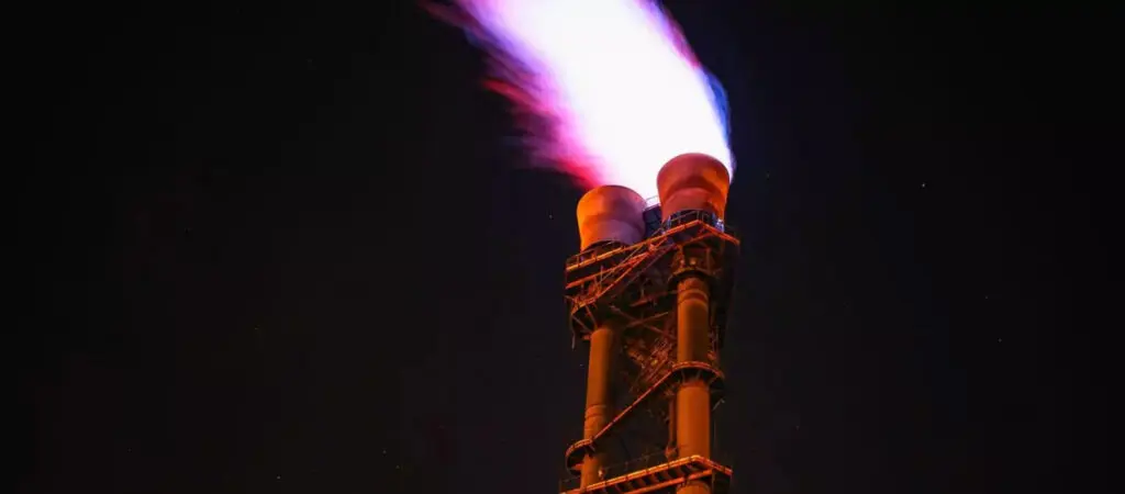 A rocket illuminated at night, emitting a vibrant red and blue flame.